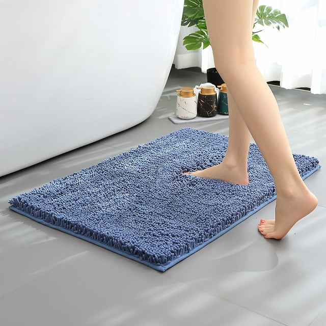 Hitime Soft Chenille Bath Mat in blue, measuring 20x30 inches, placed on a bathroom floor. The mat features ultra-absorbent chenille fabric with a textured TP rubber backing for non-slip safety. A person steps on the plush, quick-drying surface, showcasing its comfort and moisture absorption. Suitable as a bathroom runner to enhance decor and keep floors dry.