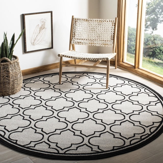 Safavieh Amherst Wilson Tapis Géométrique pour Aire, un Tapis Rond durable Intérieur-Extérieur avec un Motif Géométrique Noir et Blanc, Tissé Mécaniquement en Polypropylène, Exposé sur un Plancher de Bois Clair avec une Chaise Tissée et une Plante en Pot dans un Coin Lumineux, Convient aux Zones à Fort Achalandage à la Maison Ou au Bureau.