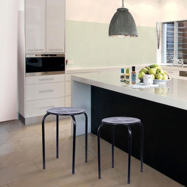 Metal Stool with matte black powder-coated finish, round perforated seat, and four straight legs with non-marring feet, shown in a modern kitchen with white island countertop and pendant light, stackable for space-saving and suitable for indoor or outdoor use, also ideal as a plant stand or side table.