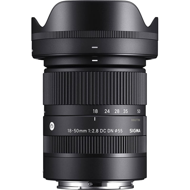 Sigma 18-50mm F2.8 DC DN Contemporary lens for Sony E-mount cameras, featuring a compact and lightweight design. The lens offers a versatile 27-75mm full-frame equivalent zoom range with a constant f/2.8 aperture. Visible are the focus and zoom rings, along with the lens markings for focal lengths and aperture. The lens includes three high-precision aspherical elements and a low dispersion element for excellent optical quality. Autofocus is powered by a quiet stepping motor, ideal for video and fast-moving subjects. The lens is shown with its rounded seven-blade diaphragm for smooth bokeh effects.