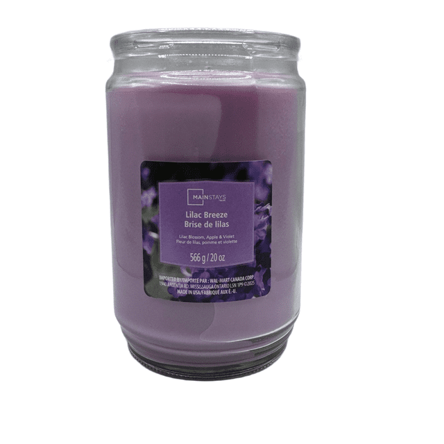 MAINSTAYS PL Lilac Breeze Scented Single-Wick Glass Jar Candle, 20 oz, containing purple paraffin wax in a clear glass jar with a label showing lilac blossom, apple, and violet fragrance notes, suitable for home décor and enhancing relaxation.