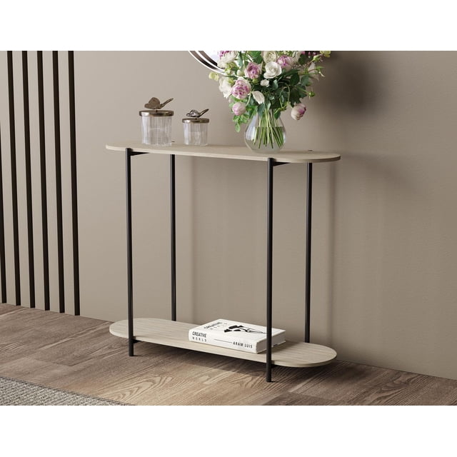 Premium Console Table for Entryway in taupe with narrow oval top and bottom shelves supported by slim black metal legs in an industrial style. The top shelf holds a glass vase with pink and white flowers and two decorative glass jars with metal lids, while the bottom shelf stores a book titled Creative World by Aram Luis. Suitable for small spaces and versatile use in living rooms, hallways, or bedrooms.
