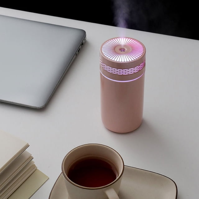 Chmadoxn Home Appliances Cool Mist Humidifiers for Babies, a compact and quiet pink ultrasonic humidifier with LED night light, placed on a white desk next to a laptop, cup of tea, and notepad. Designed for bedroom nightstands and small spaces, featuring a 320ml water tank and USB power supply.