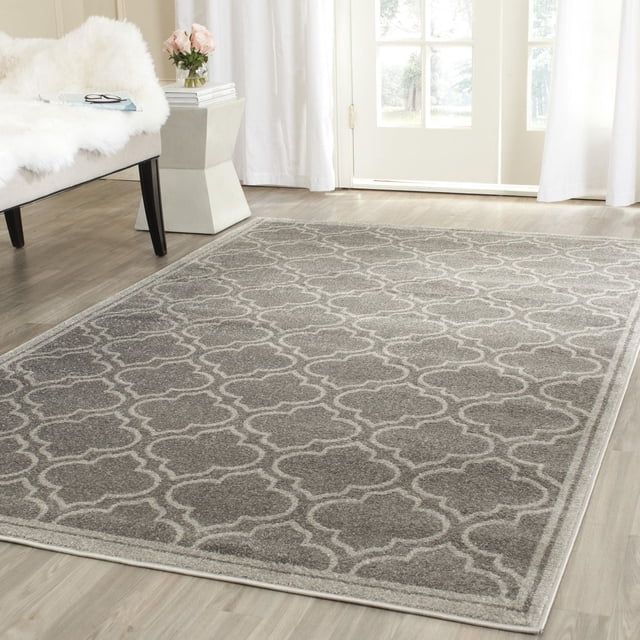 Safavieh Amherst Wilson Geometric Area Rug on light wood flooring in a bright room, featuring a grey and white geometric trellis pattern with durable polypropylene cut pile, suitable for high-traffic indoor or outdoor use.