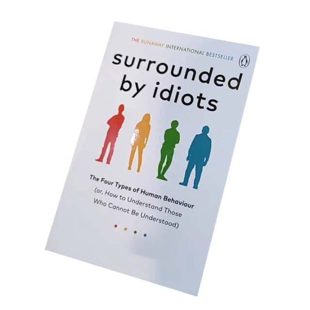 Le Livre « Entouré d'Idiots : Quatre Motifs de Comportement Humain » par ECPECAD, Présentant une Couverture Blanche avec des silhouettes de Quatre Individus en Rouge, Jaune, Vert et Bleu, Représentant Différents types de Personnalité. Le sous-Titre Se Lit comme Suit : « les Quatre types de Comportement Humain (Ou, Comment Comprendre Ceux Qui Ne Peuvent Pas Être Compris) ». Le Livre Est Imprimé sur du Papier de Haute Qualité avec un Texte Clair et Mesure Environ 20 x 13 cm.