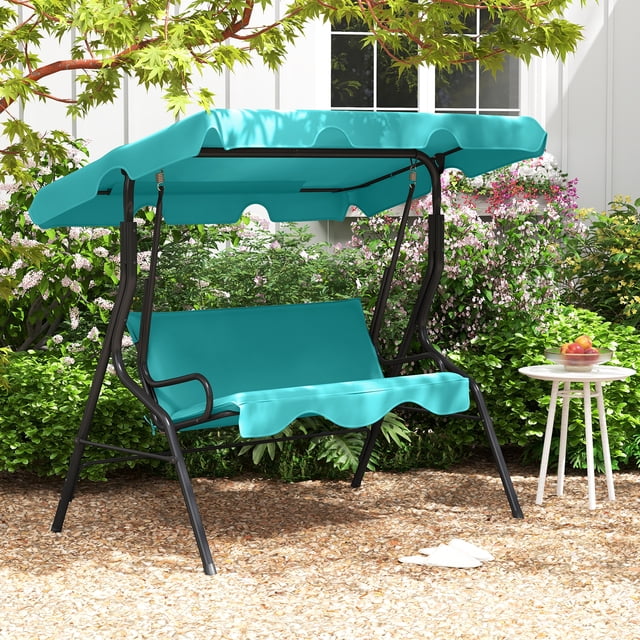 Costway Patio 3 Seats Canopy Swing Glider Hammock Cushioned Backyard Blue. This outdoor swing features a sturdy A-shaped metal frame with a rust-proof powder-coated finish, a 45° adjustable polyester canopy for sun and drizzle protection, and a cushioned seat with curved armrests for comfort. The swing accommodates up to three people with a weight capacity of 660 lbs. It is shown in a backyard setting with lush greenery and a small side table nearby.