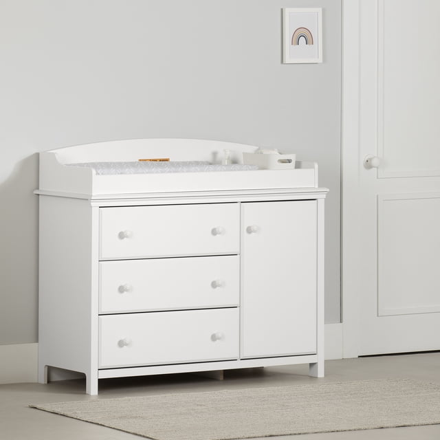 South Shore Cotton Candy Changing Table with Removable Changing Station in pure white, featuring three large drawers with metal slides and a closed cabinet, topped with a removable rim and a patterned changing pad, set against a light grey wall with a framed rainbow print and a white door nearby.