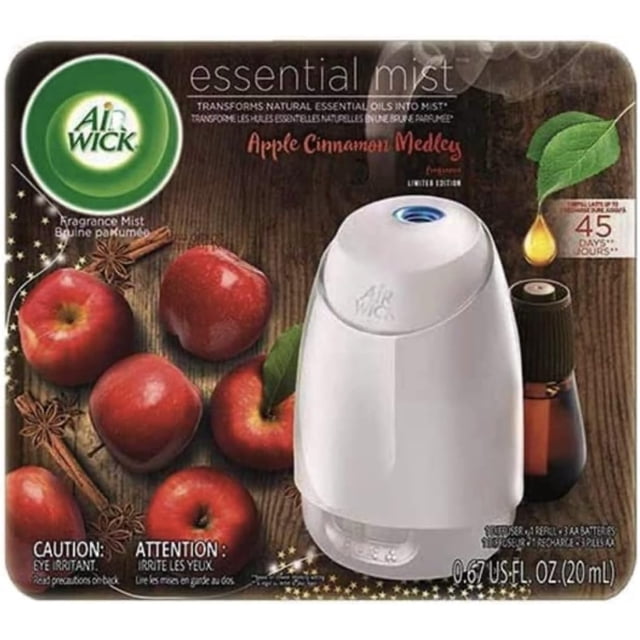 Air Wick Essential Mist diffuser with one Apple Cinnamon Medley refill, featuring a white diffuser and a 20 mL refill bottle. The packaging highlights the fragrance of fresh apples, warm cinnamon, nutmeg, and sweet vanilla, with a runtime of up to 45 days on the low setting. The background includes imagery of apples, cinnamon sticks, and essential oil droplets.