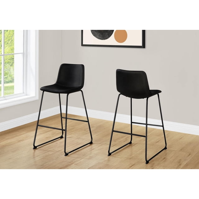 Monarch Specialties office chair bar height stool with black leather-look cushioned seat and curved backrest on a slim black metal frame with footrest, suitable for kitchen island seating or standing desks in modern rooms with light wood flooring.