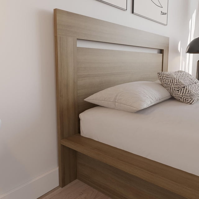 Nexera Malibu Headboard crafted from engineered wood with natural grain finish, featuring clean lines and minimalist design, shown attached to a bed frame with white bedding and patterned pillows in a bright bedroom corner.
