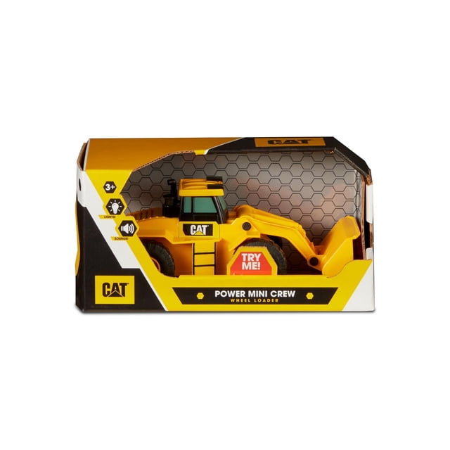 CAT Power Mini Crew front loader toy vehicle in yellow with black wheels and articulated bucket, displayed in branded packaging with hexagonal pattern and 'Try Me' button for lights and sounds, suitable for children aged 3 and up.