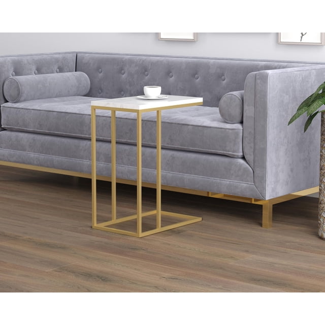 Safdie & Co. Accent Table C-Shaped Marble Gold Metal with a white marble top and gold metal base, placed beside a grey velvet tufted sofa with cylindrical pillows on a wood floor, suitable for living room use and holding snacks, drinks, or a laptop.