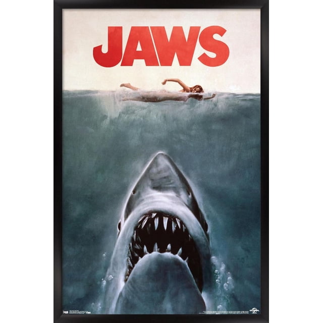 Jaws - One Sheet Wall Poster, 22.375" x 34", black-framed glossy print featuring a high-resolution image of a great white shark ascending through deep blue water toward a female swimmer at the surface beneath bold red JAWS text, perfect for wall décor in bedrooms, offices, or dorms and suitable for adding dramatic style to party decorations.