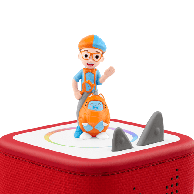 Tonies Blippi Figurine Audio en Tenue Bleu et orange Debout sur un Haut-Parleur Toniebox Rouge avec une Toupie Blanche Présentant un design Circulaire Multicolore et Deux Boutons de Commande Triangulaires Gris, Tenant un Personnage en Forme de Chat orange et Bleu, Idéal pour le Jeu Éducatif Sans Écran pour Enfants.