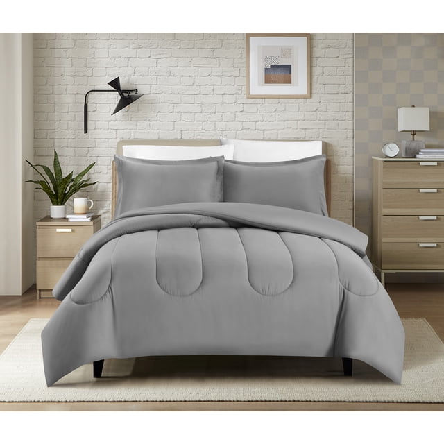 Swift Home Luxury 8 Piece Bed in a Bag, All Season Complete Bedding Set, Queen, Light Gray on a queen bed with a smooth light gray comforter featuring rounded stitched patterns, matching pillowcases, and shams with white pillows behind. The bedroom includes a white brick wall, black wall lamp, framed abstract art, light wood nightstand with plant and candle, and dresser with lamp and clock. Designed for year-round comfort and easy care, suitable for a coordinated bedroom look.
