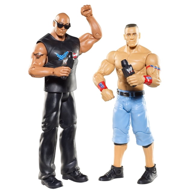 WWE Battle Pack John Cena vs. The Rock Figure 2-Pack Series 15 with two 6-inch articulated WWE action figures. One figure wears black pants and a black sleeveless shirt featuring an American flag graphic, holding a WWE microphone. The other figure is shirtless with light blue shorts and red wristbands, also holding a WWE microphone. Both have muscular builds and detailed tattoos, suitable for WWE match reenactments or display.
