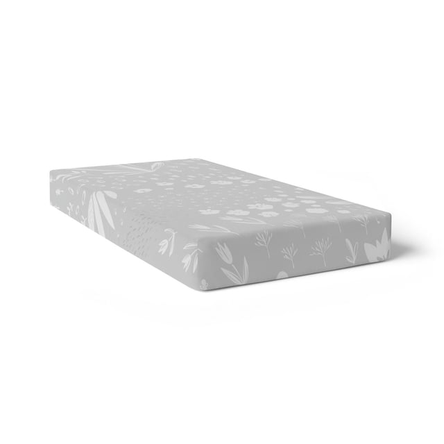 Kushies Drap-housse de Bassinette Respirant, Percale de Coton 100 % Douce Neutre Unisexe pour Bébés Garçons et Filles - Gris Lapin, Montré dans une Vue de Profil 3/4, Drap-Housse sur un Matelas de Bassinette standard. le Drap Gris Pâle Présente un Lapin Blanc et un Motif floral, Fabriqué en Percale de Coton Respirante avec des Bords Entièrement Élastiques pour un Ajustement Sécuritaire.