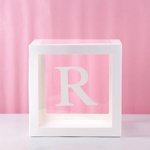 Baby Girl Birthday Party Decorations Letters Box Kit featuring a white transparent cube with the letter 'R' printed on the front. Made of eco-friendly durable paper and plastic, this balloon gift box is ideal for baby showers, birthday parties, gender reveal events, and themed celebrations. The cube is displayed against a pink backdrop.