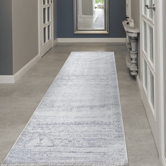BY COCOON 2'6"x8' runner rug shown in a hallway with a light grey and white intricate design. This washable rug is crafted in Turkey with durable cotton and chenille materials, featuring a non-slip backing for added safety. The low pile height of 0.2 inches makes it perfect for high-traffic areas, entryways, and under furniture. Resistant to stains, fading, and shedding, it is easy to clean and suitable for homes with children and pets. The rug includes fringe accents for a stylish finish.