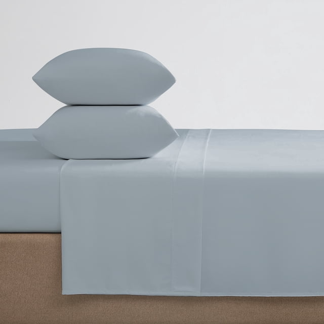 Hometrends 100% Cotton Pillowcases in light blue, stacked two high on a bed with matching fitted and flat sheets, made from wrinkle- and fade-resistant cotton with 400 thread count, standard size with envelope closure, displayed on a beige fabric bed base.
