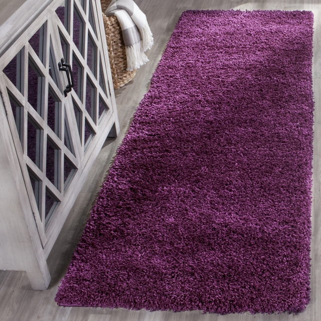 Safavieh California Tapis Shag Uni en Peluche pour Aire, Violet Riche avec un Empilage de Polypropylène super dense de 4,5 Kg/m2, Exposé sur un Plancher de Bois Clair à Côté d'Une Armoire en Bois Grise avec des Portes en Verre et un Panier Tressé Tenant une Couverture Rayée Pliée, Convient pour Ajouter Douceur et Chaleur aux Intérieurs de la Maison.