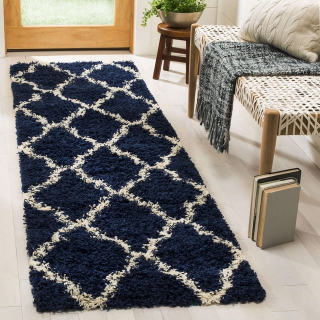 Safavieh Dallas Tapis Shag Géométrique Logan pour Aire avec Motif de Carreaux Marocains Bleu Marine et Ivoire, Polypropylène Tissé Mécaniquement avec Poils Shag Doux, Posé sur un Plancher de Bois Franc Clair Près d'Un Banc Tressé avec Jeté Gris et Livres, Idéal pour Ajouter une Touche de Confort aux Entrées Ou aux Couloirs.