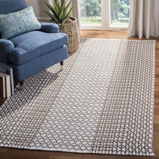 Safavieh Montauk Cara Tapis Géométrique pour Aire avec Coton Tissé à Plat en beige et Blanc Motif Géométrique, Posé sur Plancher de Bois Franc à Côté d'Un Fauteuil Rembourré Bleu avec un Oreiller Bleu Texturé et un Cache-Pot Panier Tressé avec une Plante Verte Près d'Une Fenêtre avec Rideaux beige, Idéal pour décor Côtier et Contemporain.