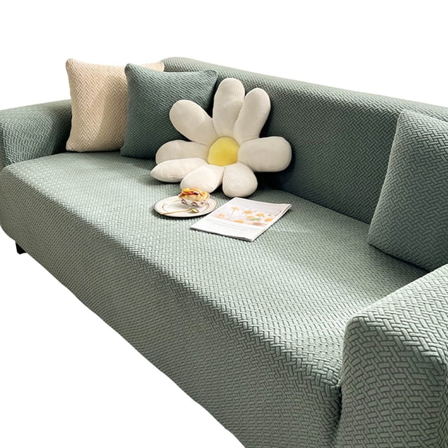 Pet Sofa Covers for Furniture Sofa Cover Stretch Sofa Cover, shown in a textured knitted fabric with a beige color. The cover is designed to fit sofas ranging from 35 to 55 inches, offering high stretch and a snug fit. It is pet-friendly, non-slip, and protects against stains, pet hair, and scratches. The sofa is styled with decorative pillows, including a flower-shaped cushion, and a magazine and plate are placed on the seat.