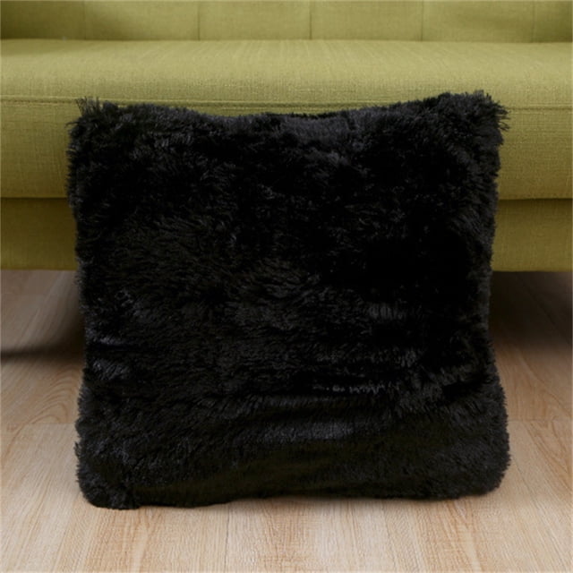 Agiferg short plush pillow cover in a solid black color, designed for sofas, beds, or backrests. The square pillow cover measures 43x43 cm and features a soft, fuzzy texture made of artificial plush, ideal for adding warmth and style to home décor. Displayed in front of a green sofa on a wooden floor.