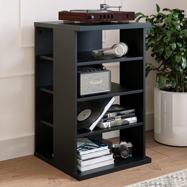 Nexera Jasper 4-Shelf Audio Tower Bookcase in matte black with four open shelves for audio and media storage, holding a wooden turntable, silver headphones, a Marshall speaker, vinyl records, fashion books, and a vintage camera, placed on a hardwood floor next to a white planter with a green plant, ideal for organizing electronic devices with easy wire access.
