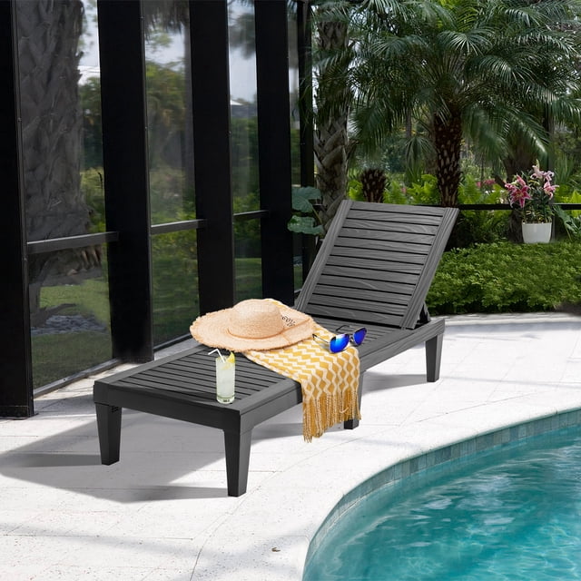 Costway Chaise Longue de Patio Chaise Inclinable en Noir, Fabriquée en Matériau PP durable et Résistant aux Intempéries, Exposée au Bord de la Piscine dans un Cadre Extérieur Luxuriant. Comprend un Dossier Réglable à 5 Positions, un design Ajouré pour la ventilation et un Cadre Léger avec 6 Pieds Renforcés Pouvant Supporter jusqu'à 400 Lb. Accessoires comme un Jeté à Motif Chevron Jaune, des Lunettes de Soleil et un Chapeau de Paille Ajoutent une Ambiance Relaxante.