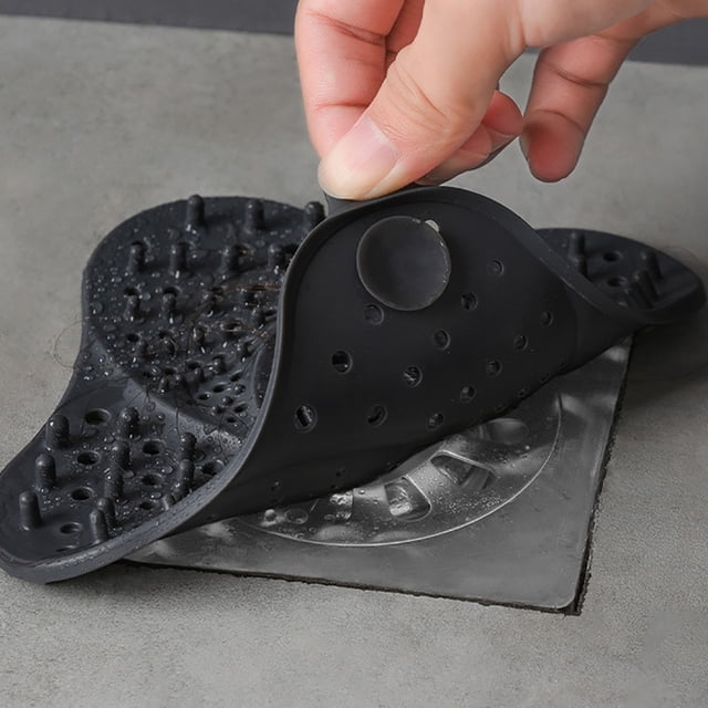 LSLJS Bathroom Hair Catcher Bath Stopper Plug Sink Strainer Filter Shower, a black TPR sink accessory designed to catch hair while allowing water to drain. Features perforations and raised grips for effective filtration. A hand is shown lifting the strainer from a sink surface, demonstrating its flexible design.