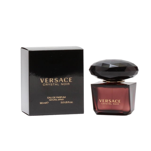 VERSACE CRYSTAL NOIR FOR LADIES EAU DE PARFUM SPRAY 3 OZ showing a front-facing dark amber glass bottle with a large faceted black cap beside its glossy black box with gold lettering, featuring a lush, sophisticated fragrance with gardenia, tuberose, musk, and amber, ideal for evening wear and special occasions.