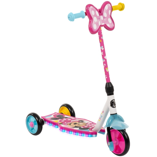 Huffy 3-Wheel Disney Minnie Preschool Scooter with LED Lights, pink toddler scooter with a large pink and white polka-dot Minnie Mouse bow on the handlebar, decorated pink stem with Minnie graphics, wide deck featuring Minnie Mouse, three wheels with blue and yellow accents, and over 40 motion-activated LED lights along the deck edge.