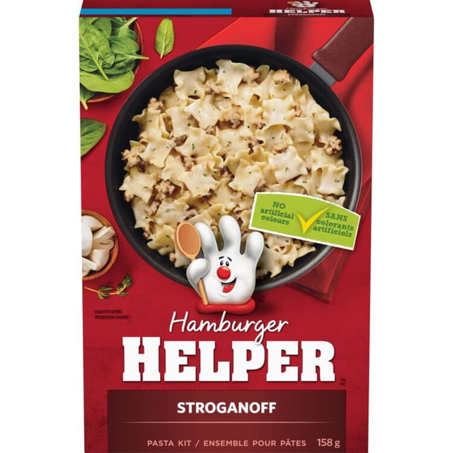 Hamburger Helper Stroganoff pasta kit box displaying creamy stroganoff pasta with mushrooms and ground meat in a black skillet on a red background with fresh spinach and mushrooms, highlighting no artificial colours and a 158 gram pasta side dish ideal for quick family meals.
