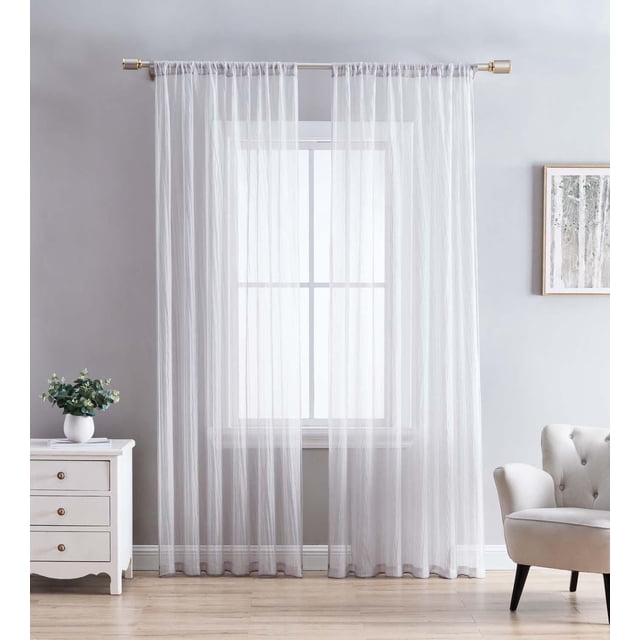 Crinkle Sheer Rod Pocket Curtains – 2 pack in soft white crushed voile fabric with a semi-sheer design that filters sunlight while preserving privacy. The curtains feature a delicate crinkled texture and easy rod pocket hanging on a gold rod in a sunlit room with light wood floors, a white dresser with a plant, and a beige tufted armchair. Suitable for adding texture and warmth to living spaces.