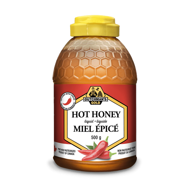 Dutchman's Gold Hot Honey 500g jar with a chili-infused honey blend. The jar features a honeycomb-textured design and a yellow secure lid. The label displays the brand logo, product name in English and French, and an image of red chili peppers, emphasizing the sweet and spicy flavor. Made in Canada with 100% natural ingredients, this unpasteurized honey is ideal for drizzling, marinating, or glazing.