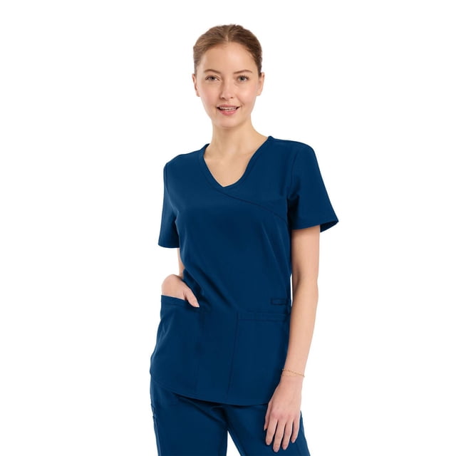 Scrubstar Core Essential Haut de Sarrau Portefeuille pour Femme en Bleu Marine Montré d'Une Vue de devant. Ce Haut à Col en V à Faux Cache-Cœur Présente un Tissu Extensible Mécanique, Deux Poches Appliquées à l'Avant, une Petite Poche Utilitaire, une Poche Arrière et une Fente pour Stylet, Conçu pour un Confort flexible et un Usage Médical Pratique.