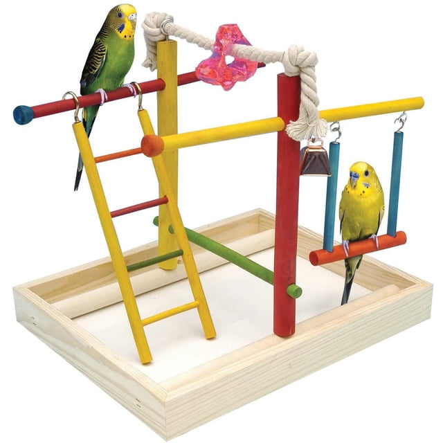 Penn-Plax Play Pen medium bird activity center with multicolour wooden frame featuring a yellow ladder, red and yellow perches, 100% cotton rope with pink acrylic star toy, copper bell, and blue-red swing, shown with two budgerigars on a natural wood base tray for indoor bird exercise and socialization.