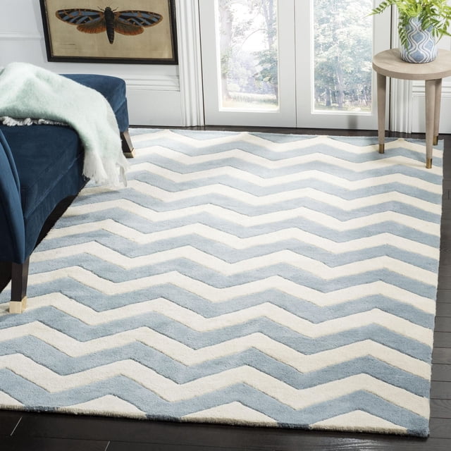 Safavieh Chatham Jake Tapis à Rayures Zigzag en Laine Tuftée à la Main avec un Poil Moyen Moelleux, Présentant des Rayures chevron Bleu Pâle et Crème sur un Plancher de Bois Franc Foncé dans une Pièce Lumineuse avec un sofa Bleu Marine et une table d'Appoint Ronde en Bois avec une Plante, Idéal comme Tapis d'Accent pour la Déco Contemporaine de la Maison.