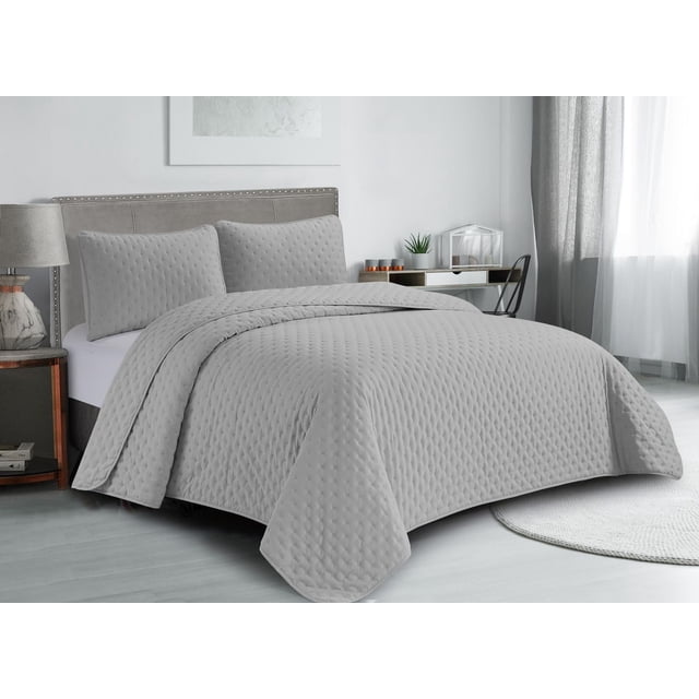 Swift Home Ultra Soft Pinsonic Quilt Set in light grey microfiber, featuring a quilt and two pillow shams with a subtle textured dot pattern. Shown on a king-size bed with a grey upholstered headboard in a modern bedroom with light wood flooring. This lightweight, hypoallergenic, all-season bedding provides cozy comfort and easy care.