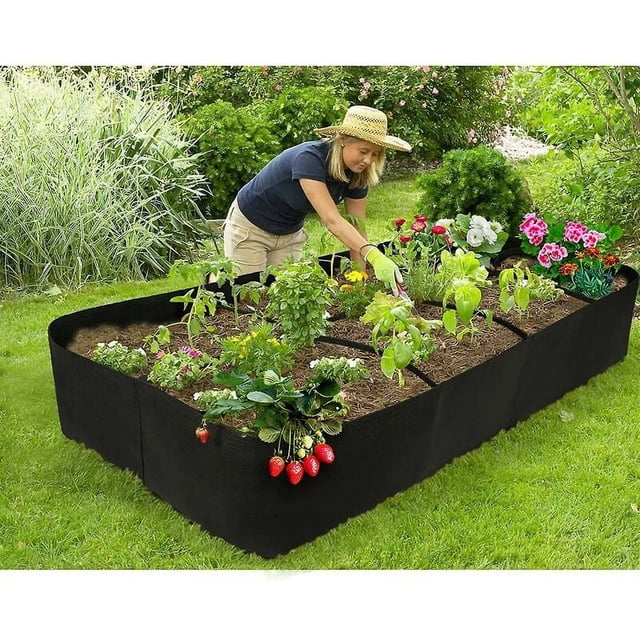 Latatta Jardinière Surélevée 0,9 x 1,8 m, Jardinière Rectangulaire en Tissu Réutilisable Faite d'Un Matériau Non Tissé Respirant, Exposée à l'Extérieur sur une Pelouse Gazonée. la Jardinière Résistante aux UV Est Divisée en 8 sections, Chaque sections Remplies de Terre et Plantées de Diverses Herbes, Fleurs et Légumes, Y Compris des Fraises. une Personne s'Occupe des Plantes, Mettant en Valeur Sa Conception Écoresponsable et Sa Polyvalence pour patios, Balcons Ou Toits.