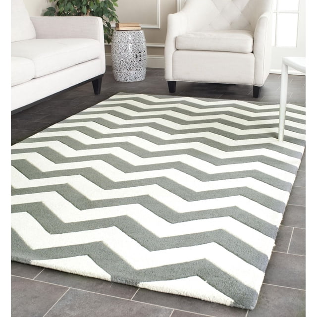 Safavieh Chatham Jake Tapis à Rayures Zigzag avec construction en Laine Tuftée à la Main et Poil Moyen Moelleux, Présentant un Motif à Rayures Zigzag Gris et Blanc. Exposé sur un Plancher de Carreaux Foncés dans un Salon avec sofa Crème, Fauteuil et table d'Appoint en Céramique. Convient à l'Utilisation de Tapis d'Accent Contemporain et Estimé pour la Douceur et la Durabilité.