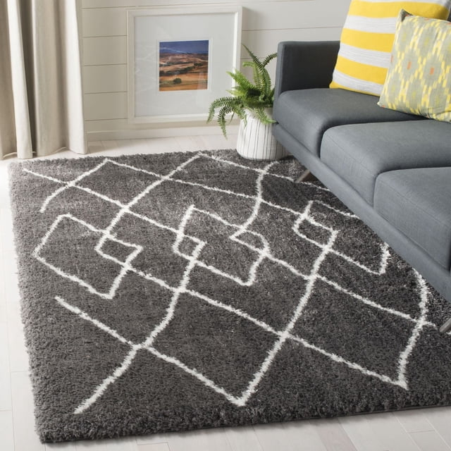 SAFAVIEH Flokati Tapis Abstrait Gisselle Gris Foncé avec Lignes Géométriques Blanches, Présentant une texture shag en Laine Douce et un Endos en Toile de Coton durable, Posé sur un Plancher de Bois Franc Clair à Côté d'Un sofa Gris Moderne avec des Coussins à Rayures Jaunes et à Motifs, une Fougère en Pot dans un Cache-Pot Blanc, et une photo de Paysage Encadrée contre un Mur shiplap Blanc, Idéal pour Ajouter Chaleur et texture aux Salons Ou Chambres.