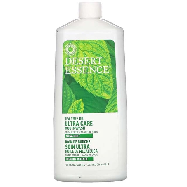Desert Essence Tea Tree Ultra Care Méga Menthe Rince-Bouche dans une Bouteille Blanche de 473 ml avec une Étiquette Verte Présentant des Feuilles de Menthe, une Formule Sans Sucre Ni Alcool Qui Illumine les Dents, Rafraîchit l'Haleine et Apaise les Gencives, Convient aux Soins Buccodentaires Quotidiens.