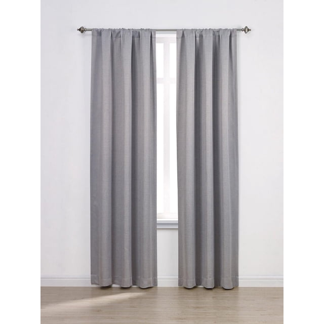 Mainstays Chambray Blackout 63" Window Curtains Panel Pair in grey stone, featuring 100% polyester microfiber with a heathered texture and triple foam backing for full blackout, hanging on a metal rod with finials in a room with light wood flooring and white walls, ideal for bedroom light control and privacy.