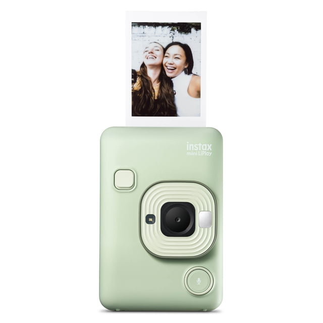 FUJIFILM INSTAX MINI LiPlay Hybrid Instant Camera and Smartphone Printer in Matcha Green, front-facing view showing the camera lens with cream textured surround, flash, shutter and microphone buttons, ejecting an instant photo of two people against a white brick wall, compact and lightweight design for instant film photography and smartphone printing with Bluetooth control.