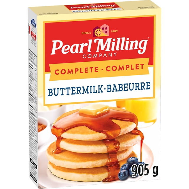 Pearl Milling Company Complete Pancake & Waffle Mix Buttermilk 905 g box showing a stack of four fluffy pancakes topped with butter and maple syrup dripping down the sides, fresh blueberries on the plate, and a glass of orange juice in the background, suitable for making light and fluffy pancakes and waffles.