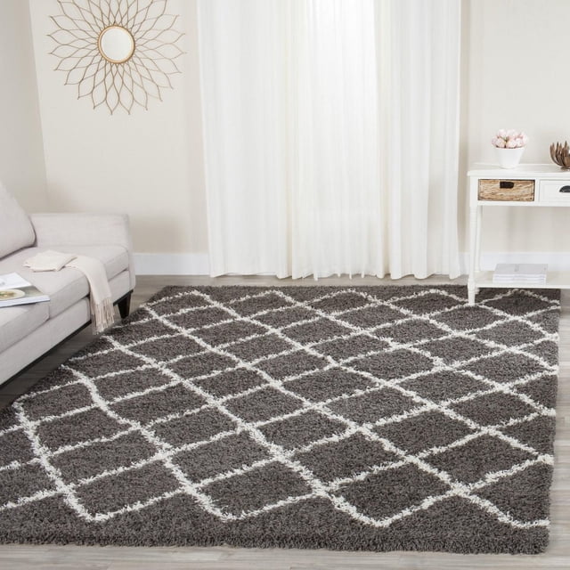Safavieh Layla Geometric Plush Shag Area Rug featuring a dark grey base with a white diamond pattern, displayed in a contemporary living room with a light grey sofa and white side table. The plush synthetic fibers provide a dense, soft texture ideal for high-traffic areas and adding warmth to modern decor.