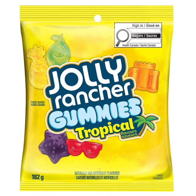 JOLLY RANCHER GUMMIES Tropical Flavours 182g bag showing colorful tropical-shaped gummy candies including pineapple, pear, starfish, sunglasses, and sandcastle on a bright yellow package with Health Canada sugar warning, offering bold mango, lime, passion fruit, golden pineapple, and fruit punch flavours.